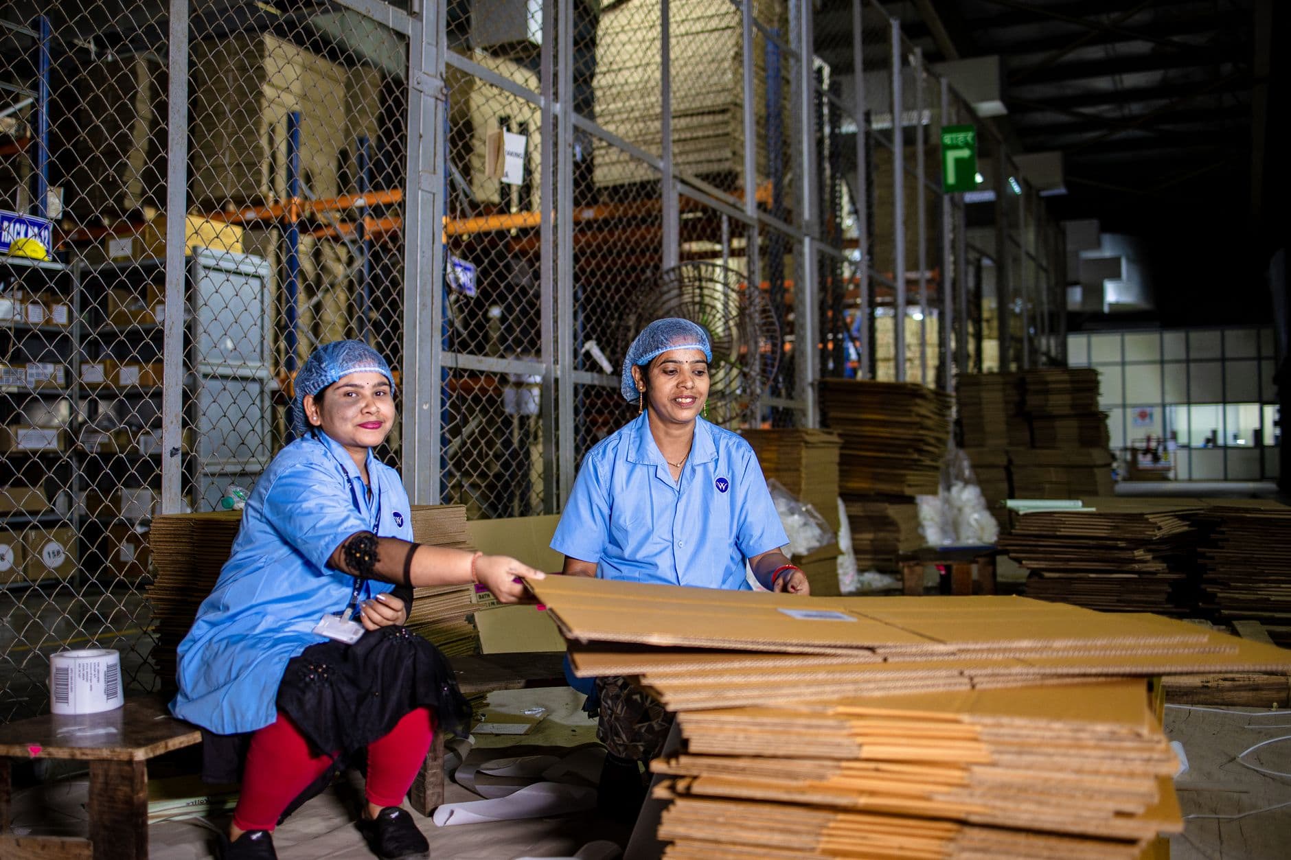 warehouse workers handling boxes among stocked shelves